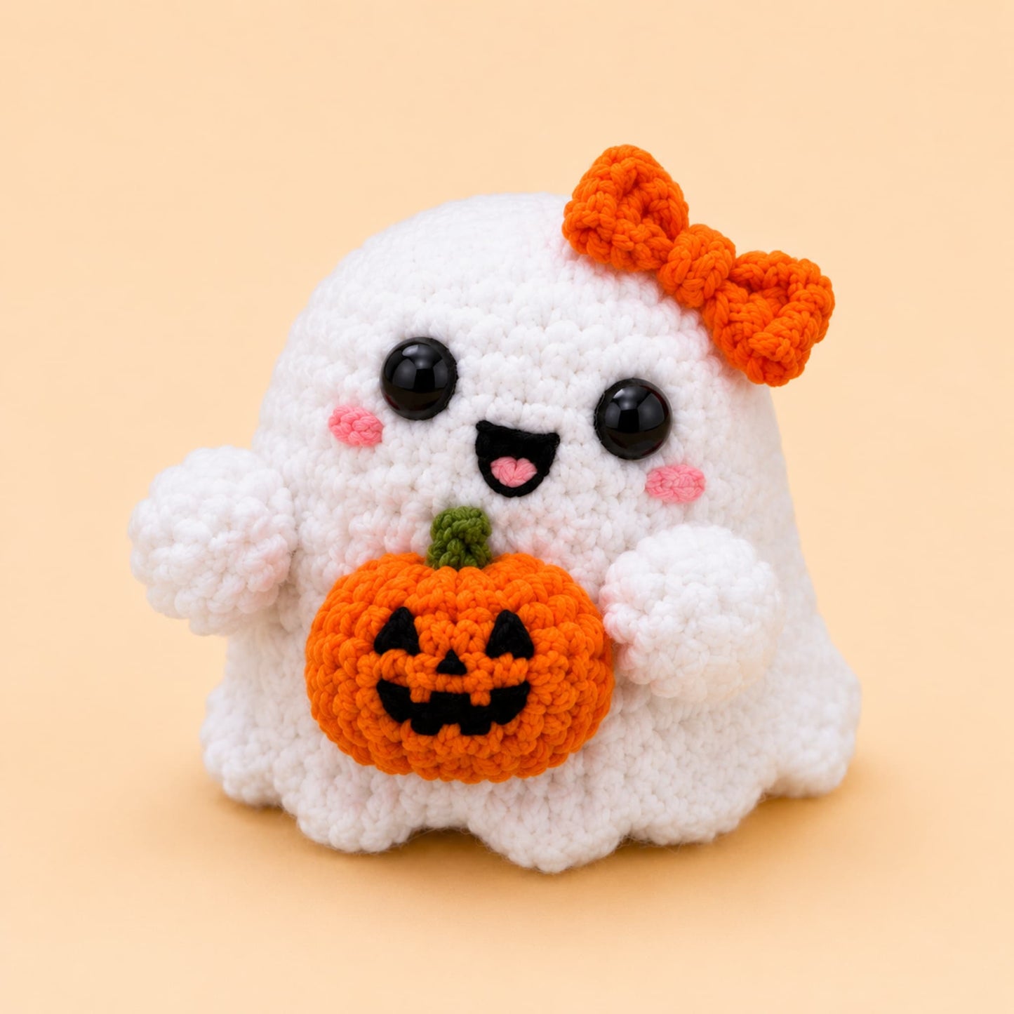 Handmade crochet white ghost plush with an orange bow holding a little jack-o-lantern