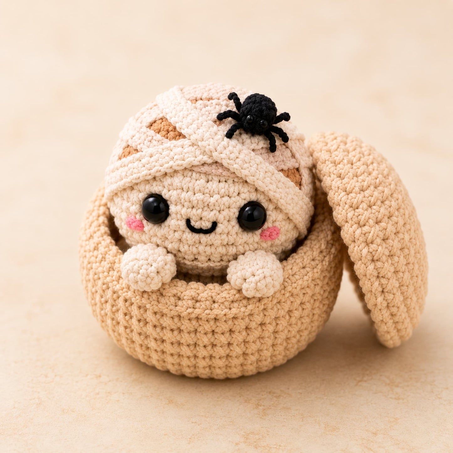 Handmade crochet mummy dumpling plush wrapped in bandages with a small black spider on top