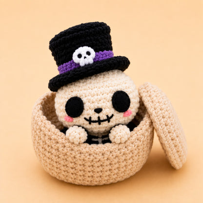 Handmade crochet skeleton dumpling plush in a black top hat sitting in a steamer basket