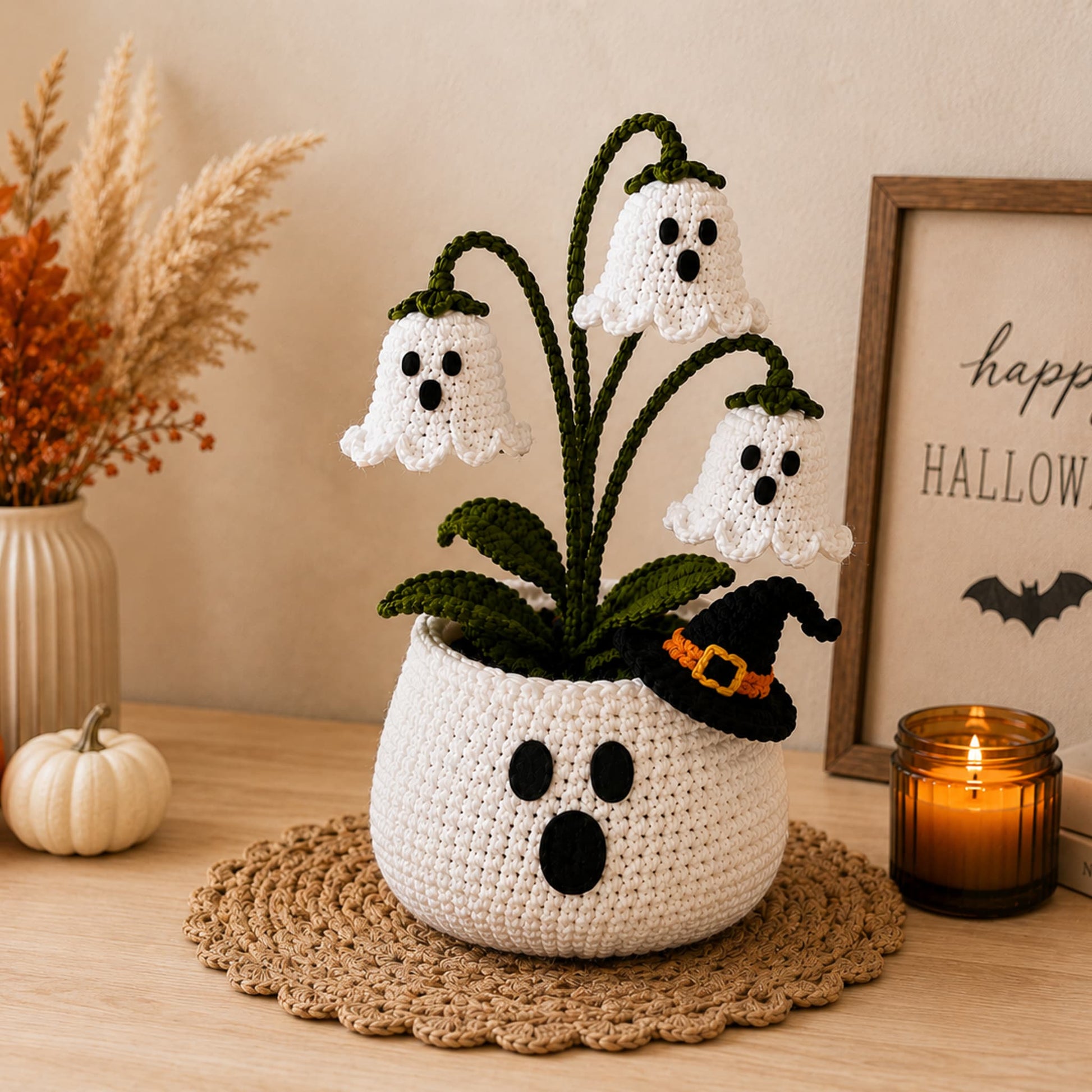 Handmade crochet white ghost flower pot with drooping ghost blooms and a tiny black witch hat on the rim