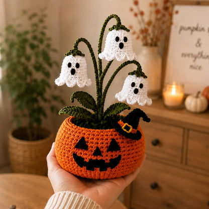 Hand holding a small crochet jack-o'-lantern flower pot to show its size against an open palm